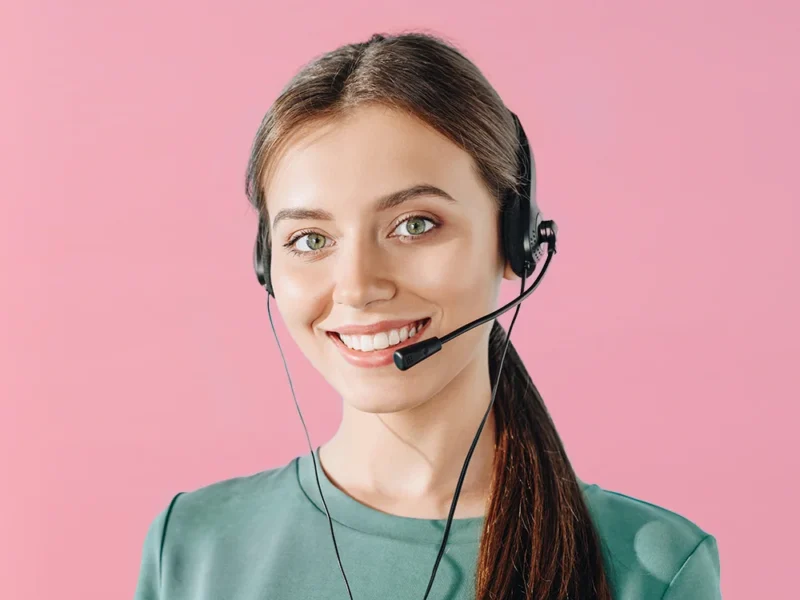 A female American AnsweringService.com virtual receptionist on a pink background.